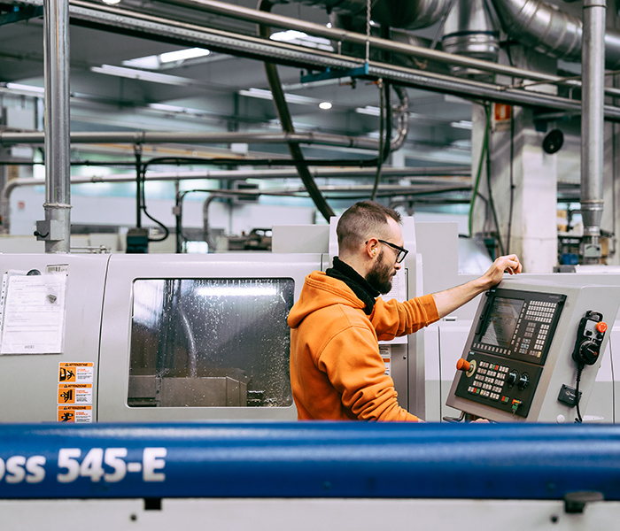 operatore CNC, macchina industriale, produzione avanzata, lavorazione meccanica, controllo macchine.
